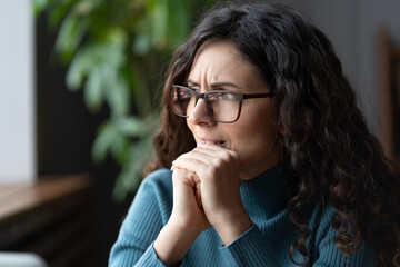 Scared and worried businesswoman or student thinking of mistake at work, waiting for email from boss or leader. Overwhelmed millennial woman in glasses in office look in window stressed biting lips