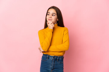 Little girl isolated on pink background thinking an idea while looking up