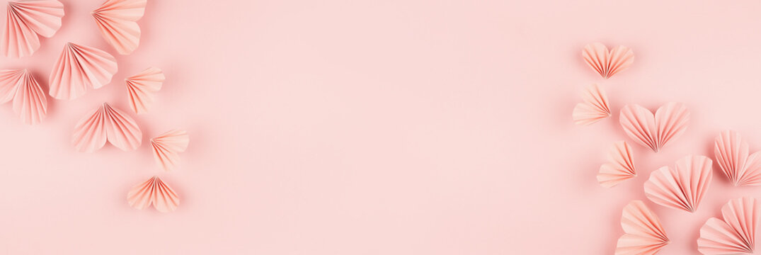 Valentine day banner - flow of flying gentle pink paper ribbed hearts on soft light pink background, top view, copy space, border. Festive love backdrop for website, design, card, poster, text.