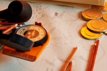 Compass, coins, and smoking pipe on the old treasures map. Sailing and treasure hunting