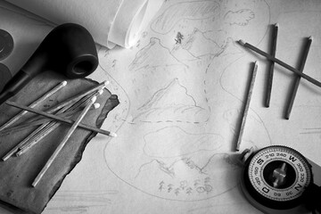 Black and white picture of adventurer desk with treasure map and compass. Vintage still life of an...