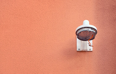 Damaged cctv video camera on building wall. Parts of pan tilt zoom camera hanging on wall mount bracket. Broken surveillance camera on building wall. Damaged CCTV security cam, vandalism concept