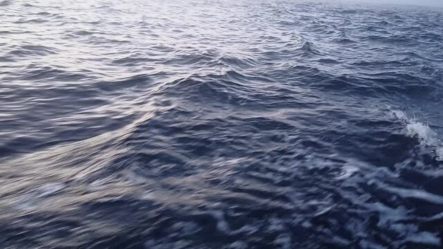 The texture of the seething blue sea salt water with waves, spills, bubbles, foam after a swiftly floating boat in the Barents sea in winter