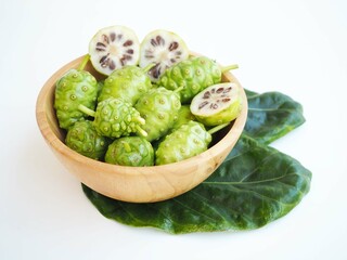 Fresh noni fruit or morinda citrifolia and slices in wood bowl on white background. closeup photo, blurred.