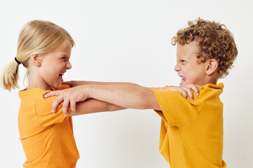 Small children in yellow t-shirts standing side by side childhood emotions light background unaltered