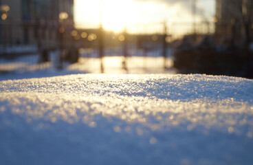 Snow surface is a close-up of snow and flakes. Crust of snow. Blurred objects background.