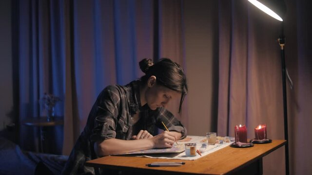 Beautiful girl draws a mandala in a room 
