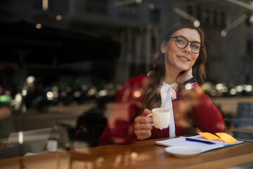 Beautiful young woman using digital tablet in cafe. Happy smiling woman enjoy in fresh coffee.