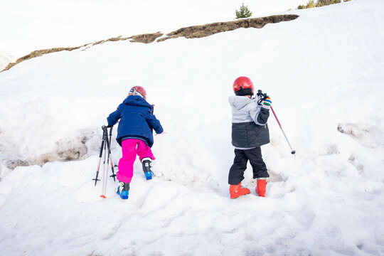 White snow picture whith a boy and a girl learning to ski with their family.