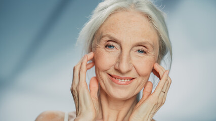 Medium Portrait: Senior Woman Looking at Camera, Touching, Massaging Beautiful Face, Smiling....
