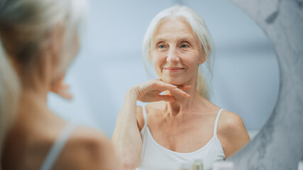 Beautiful Senior Woman Morning Bathroom Routine, Looks into Mirror Touches Her Neck with Sensual...