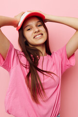 cheerful young girl with a cap on her head in a pink t-shirt