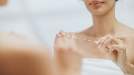 Anonymous Portrait of Beautiful Asian Woman Uses Dental Floss to Clean Her Natural White Teeth, Smiles in Bathroom. Morning routine, Dental Hygiene, Wellness, beauty.
