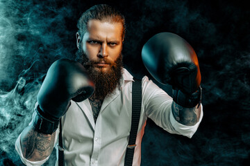 Fototapeta na wymiar bearded man in white shirt wears boxing gloves and ready to fight. Man self defense. Studio shot