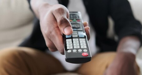 Male hand using remote control to change channels on television at home