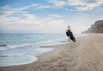 beautiful girl in a long black vintage dress running along the seashore