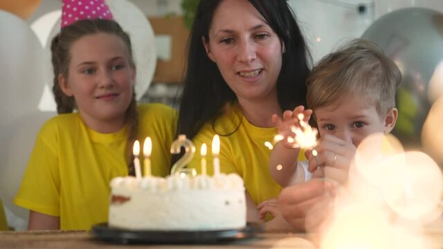 birthday. happy family on holiday party. fun parents and childs with baby getting ready to blow out birthday cake with candles. happy family at birthday. baby blows out the candles on the cake