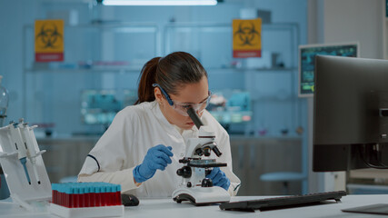 Portrait of chemist working with microscope in laboratory, to develop science experiment. Microbiology specialist using optical tool with microscopic lens to analyze dna sample in lab.