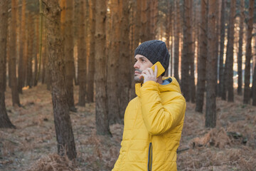 Fototapeta na wymiar a man makes a phone call in the forest. Communication in travel and nature