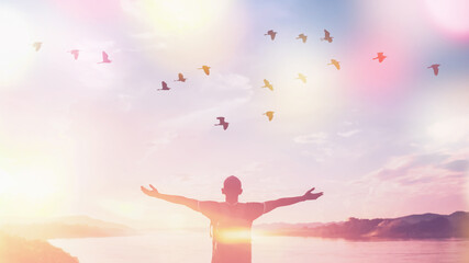 Happy backpack man raise hand up and birds flying on sunset sky at river background. Travel...