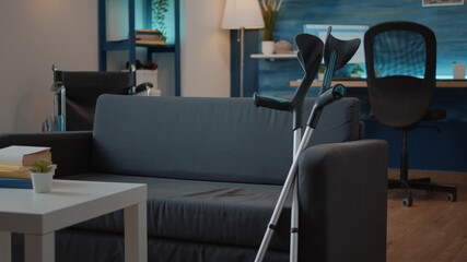 Empty space with crutches on sofa and walking equipment to help with chronic disability. Object used for mobility and accessibility, giving support for transportation and physical recovery.