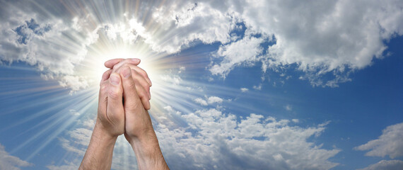 Easter Prayer to God Blue Sky Background - male hands in prayer position against a beautiful blue sky and sun burst  background with copy space for message or religious prayer  © Nikki Zalewski
