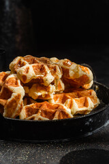 Belgian waffles with honey on a dark background