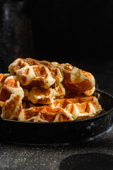 Belgian waffles with honey on a dark background