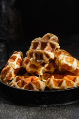 Belgian waffles with honey on a dark background