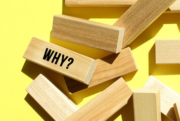 The WHY text is written on one of the many scattered wooden blocks, against a yellow background.