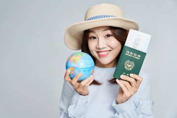 Young woman holding globe and air ticket in studio shot