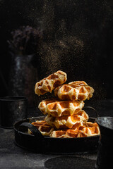 Belgian waffles with honey on a dark background
