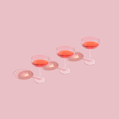 Three elegant wine glasses on pastel pink background. Trendy and minimal romantic Valentine's day...