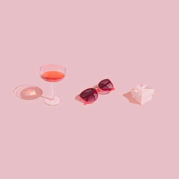 Cute and romantic self care kit made of wine glass, gift box and pink glasses on pastel background. Trendy, minimal Valentine's Day aesthetic.