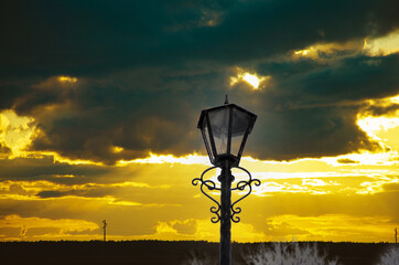 Street lamp on the embankment at sunset. Lantern on sunset sea coast. Sunset streetlamp beach scene. Street lamp on sunset beach