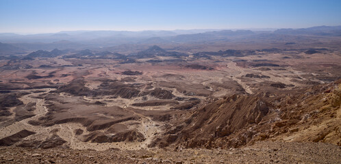 Fototapeta na wymiar Panoramic view on Crater Ramon from Mount Ardon, the Negev desert. Makhtesh Ramon - erosion crater, the most picturesque natural landmark of Israel. Orange, red and black colors of the desert.