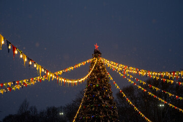 Christmas tree, colored flags and lights in the evening