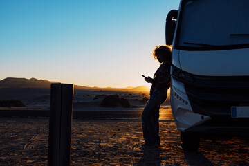 Woman in silhouette against sunset beautiful light. Travel people with camper camping car van for...
