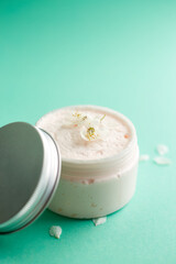 Jar of white skincare cream with Fresh spring cherry blossom flowers. Cosmetic bottles. Botanical spa treatment delicate skin. turquoise background