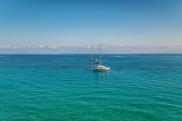 Obraz premium Anchored boat on sea surface against Corfu under blue sky