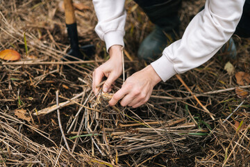 Close-up cropped shot of unrecognizable backpacker man putting brushwood on campfire to making fire...