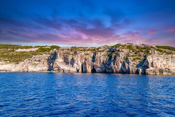 Plant-covered hill with rocks on shore of Corfu island