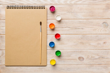 Album pages and paints, pencils, brush on a colored background. Top view with empty space. workplace for creativity. home teaching concept drawing