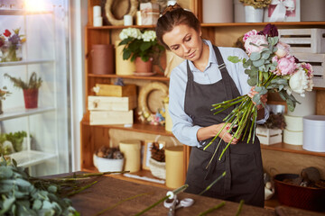 Florist making pink bouquet at flower shop