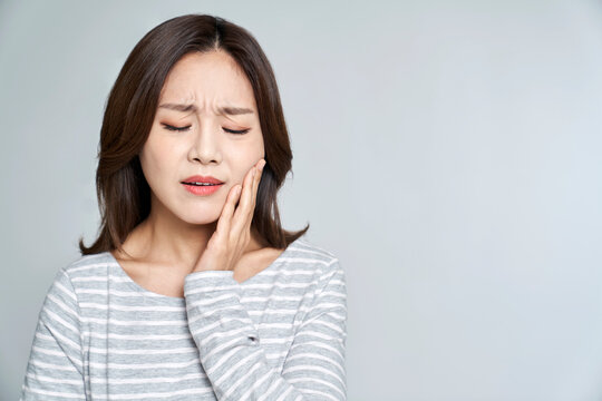 Young woman suffering from toothache with studio shot
