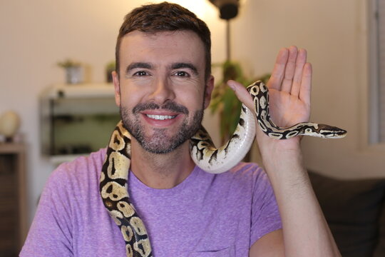 Cute man holding exotic ball python   