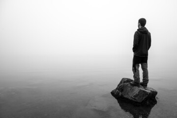 Man looking into an uncertain future at a misty and foggy lake