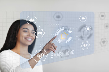 Happy african american woman controlling house functions via virtual panel