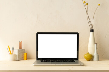 Desk with laptop screen, desk objects, office supplies, books, and plant on bright background.	