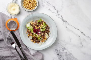 grey porcelain scandi soup bowl with traditional east european dish buckwheat salad with butter and chickpeas on marble surface and kitchen towel, top view, copy space